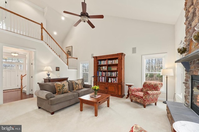 living area with stairs, high vaulted ceiling, a fireplace, and carpet