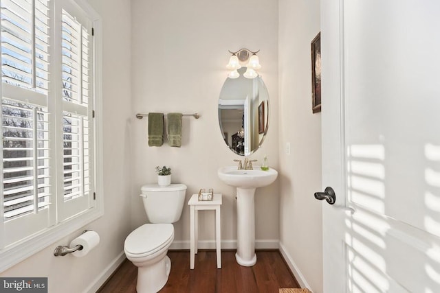 bathroom with baseboards, a sink, toilet, and wood finished floors