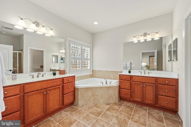 bathroom featuring a garden tub, a sink, visible vents, and tile patterned floors