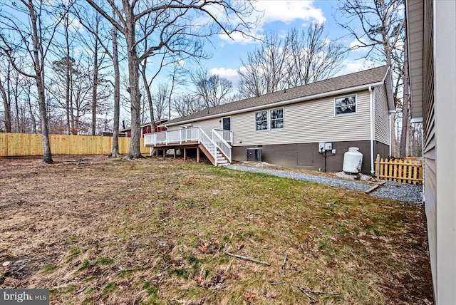 rear view of house with a lawn, a deck, central AC, fence, and stairs