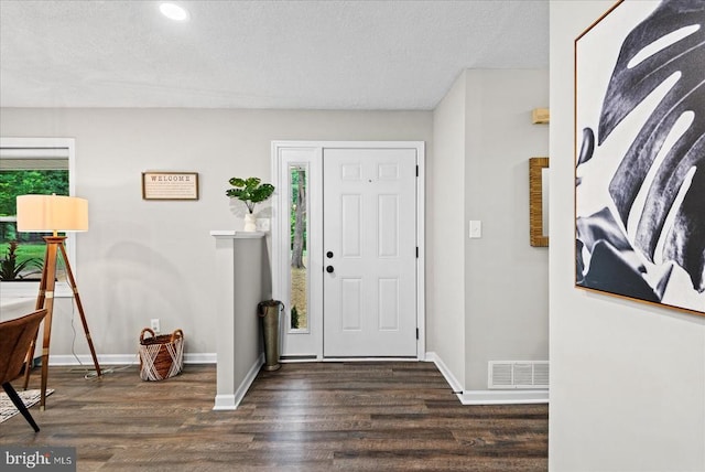 entrance foyer featuring a textured ceiling, dark wood-type flooring, visible vents, and baseboards