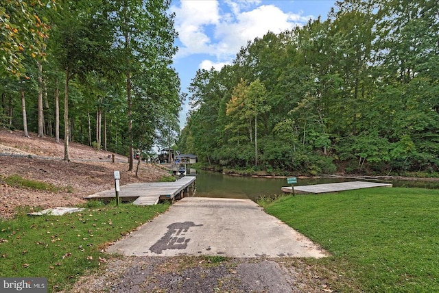 view of home's community with a lawn, a dock, and a water view