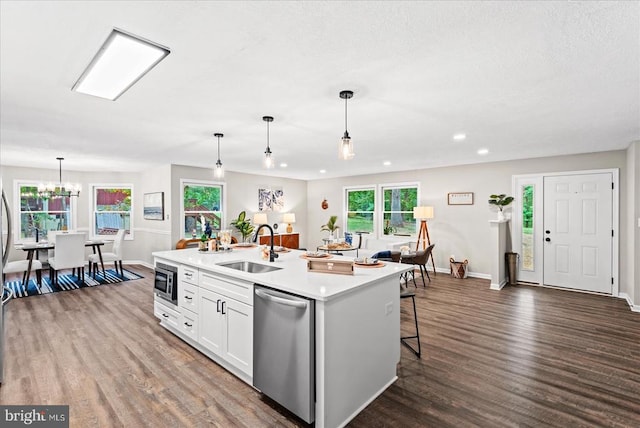 kitchen featuring light countertops, appliances with stainless steel finishes, a kitchen island with sink, a sink, and white cabinetry