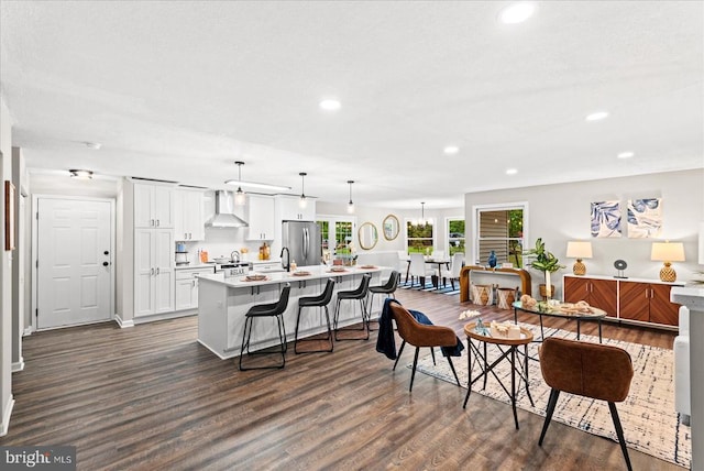 kitchen with stainless steel appliances, a spacious island, light countertops, white cabinetry, and wall chimney range hood