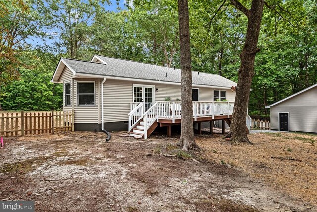 rear view of house with crawl space, roof with shingles, a deck, and fence