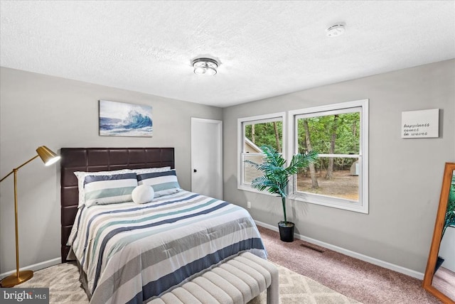 bedroom with light carpet, a textured ceiling, and baseboards