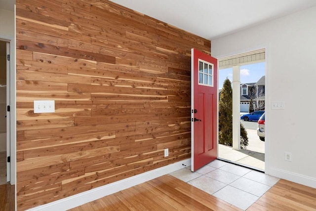 entryway with wood walls, light wood-style flooring, and baseboards