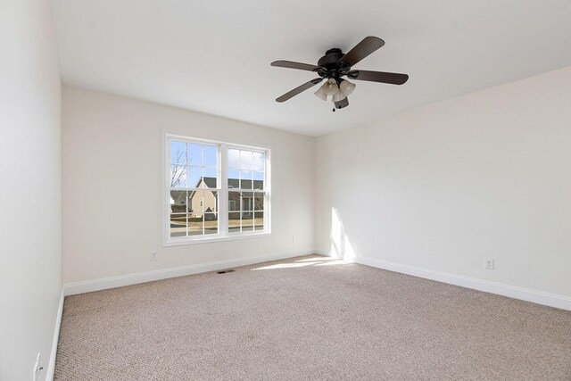 empty room with carpet flooring, ceiling fan, and baseboards