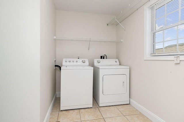 laundry room with laundry area, light tile patterned floors, baseboards, and washer and clothes dryer