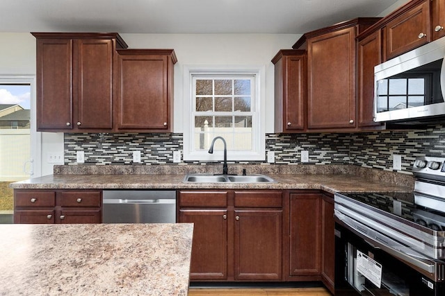 kitchen with stainless steel appliances, a sink, and decorative backsplash