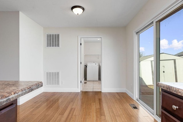 spare room with washer / clothes dryer, light wood-style flooring, and visible vents