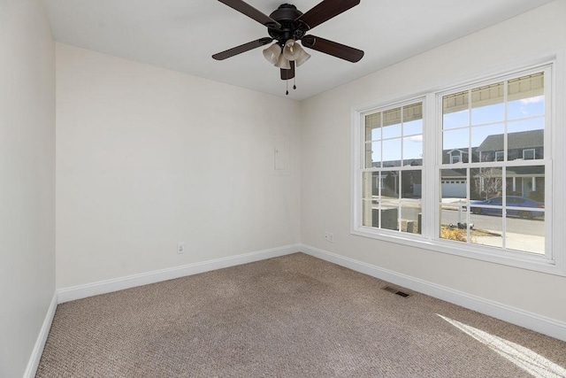 carpeted spare room with a ceiling fan, visible vents, and baseboards