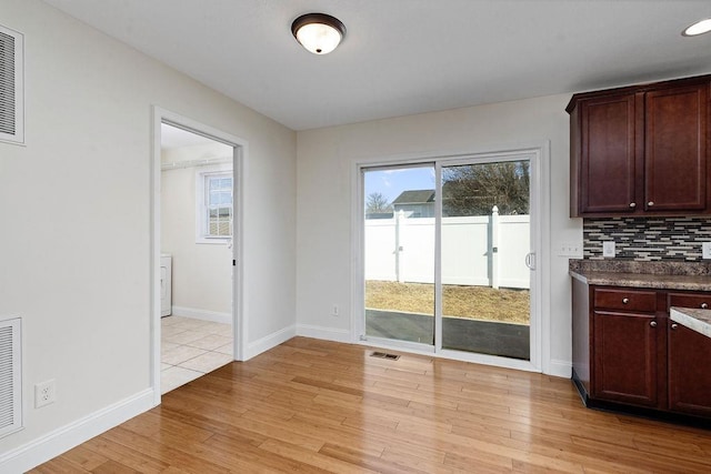 unfurnished dining area featuring light wood finished floors, baseboards, and visible vents