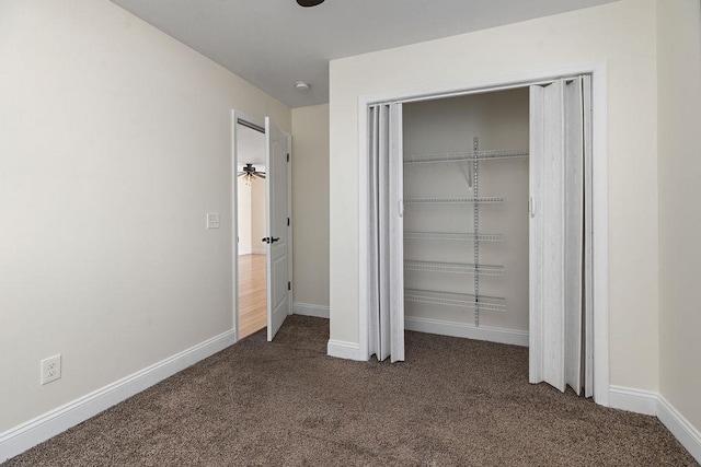 unfurnished bedroom featuring dark colored carpet, a closet, and baseboards