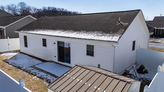 back of property with a shingled roof and fence