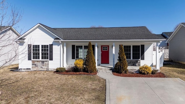 ranch-style home featuring stone siding, a shingled roof, covered porch, and a front yard