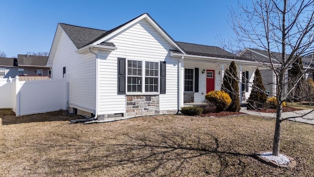 ranch-style home with roof with shingles, a front yard, crawl space, fence, and stone siding