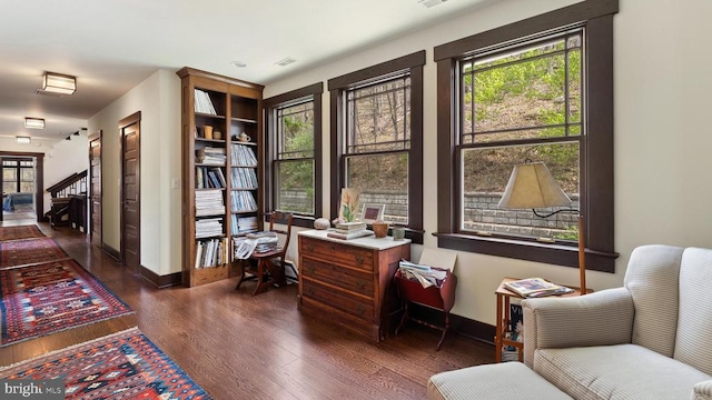 living area with plenty of natural light and dark hardwood / wood-style flooring