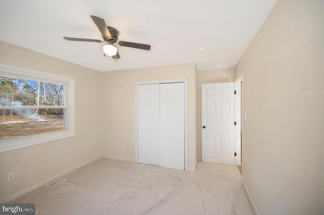 unfurnished bedroom featuring light colored carpet, ceiling fan, and a closet