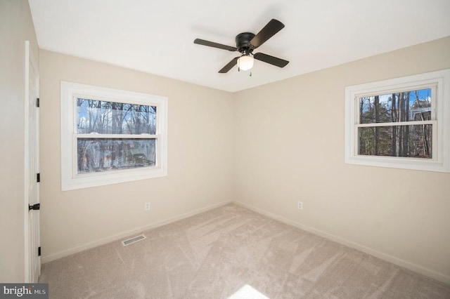 carpeted spare room with plenty of natural light and ceiling fan