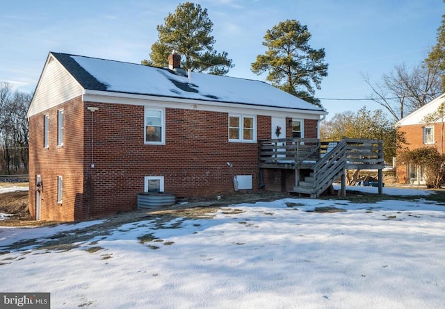 snow covered rear of property with a wooden deck