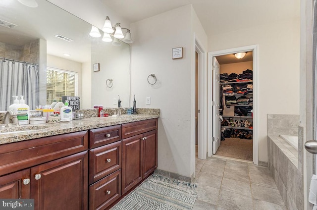 bathroom with double vanity, a sink, visible vents, and tile patterned floors