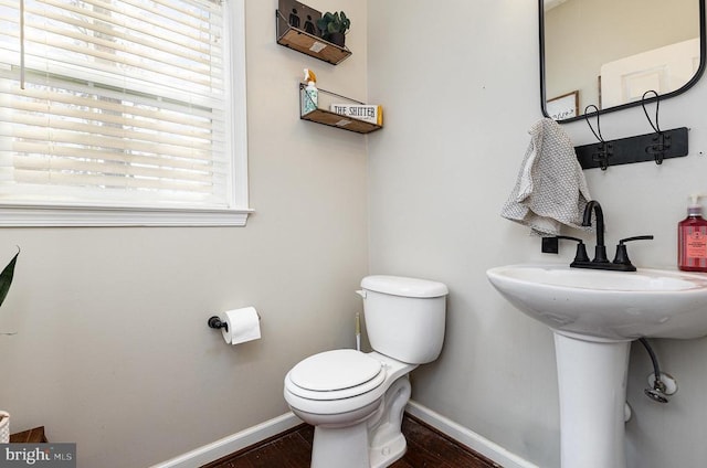 half bathroom with wood finished floors, toilet, and baseboards