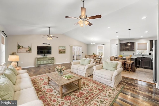 living room featuring baseboards, vaulted ceiling, recessed lighting, ceiling fan with notable chandelier, and wood finished floors