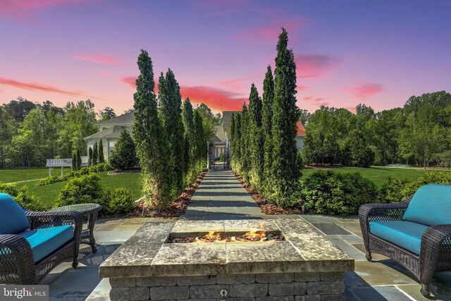 patio terrace at dusk featuring a lawn and an outdoor fire pit