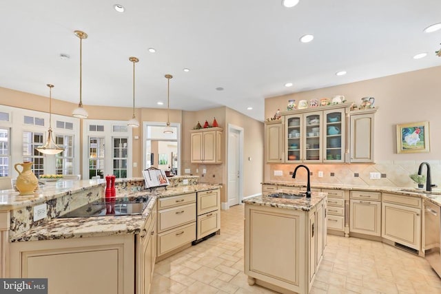 kitchen with a sink, black electric stovetop, cream cabinetry, and a spacious island