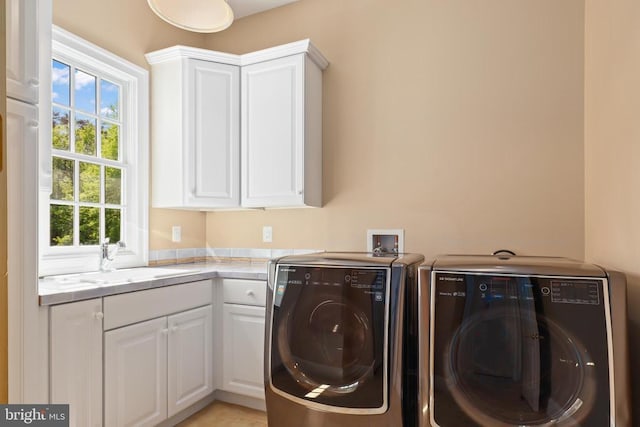 clothes washing area with cabinet space, separate washer and dryer, and a sink