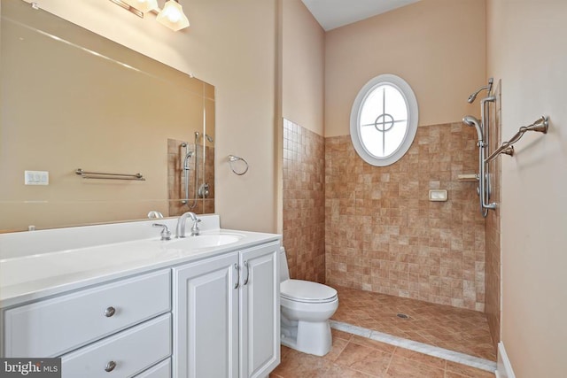 full bathroom featuring vanity, a tile shower, and toilet