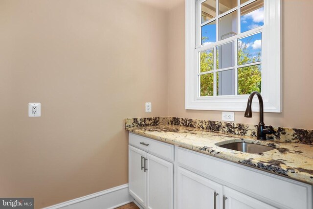 interior space featuring light stone counters, white cabinetry, and sink