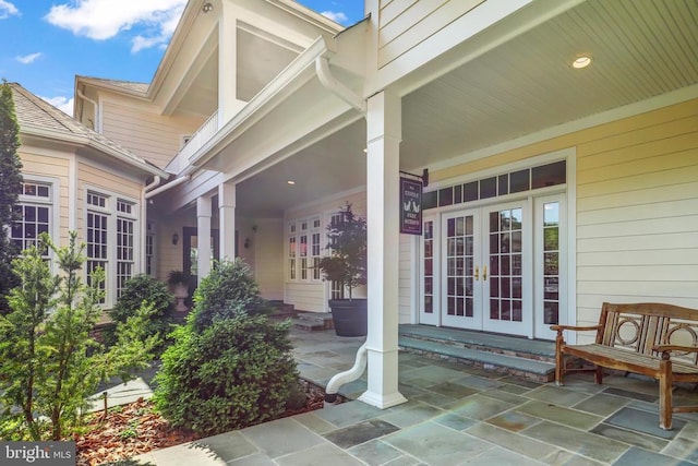view of exterior entry with covered porch and french doors