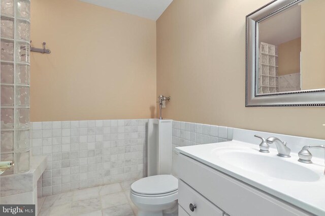 bathroom featuring tile walls, vanity, and toilet