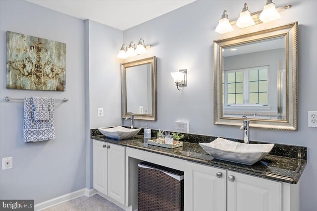 bathroom featuring double vanity, baseboards, and a sink