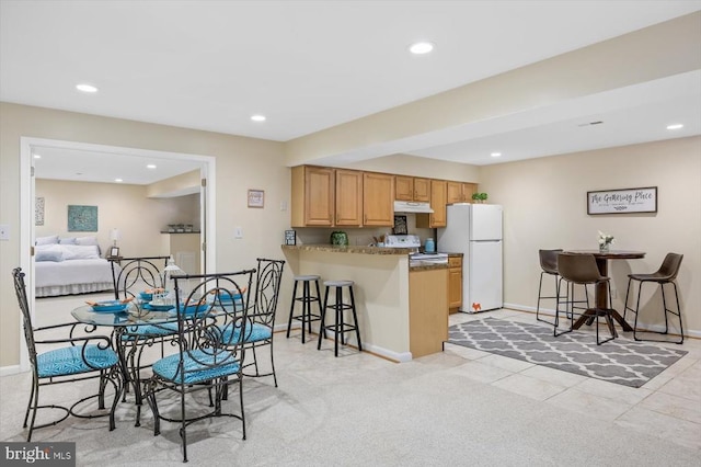 kitchen featuring a breakfast bar, recessed lighting, white appliances, a peninsula, and under cabinet range hood