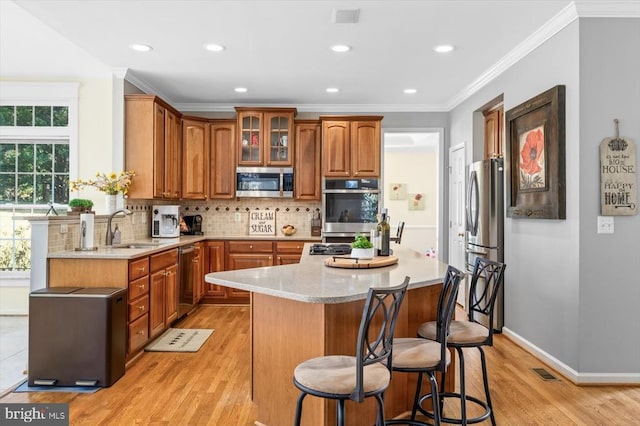 kitchen featuring a breakfast bar, stainless steel appliances, tasteful backsplash, a kitchen island, and a sink