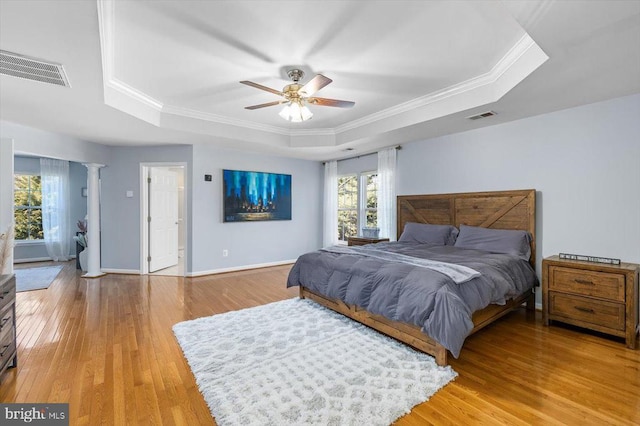 bedroom featuring a raised ceiling, visible vents, and light wood finished floors