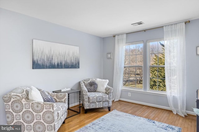 living area featuring baseboards, visible vents, and hardwood / wood-style floors