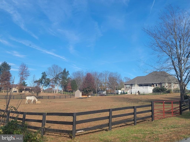 view of yard with an enclosed area, fence, and a rural view