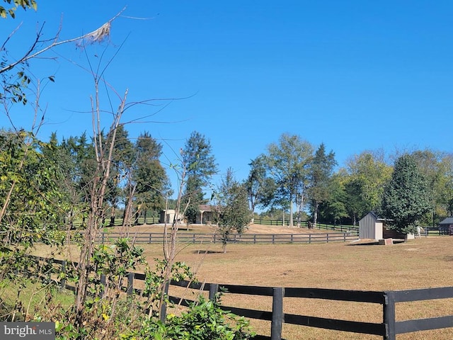 view of yard with a rural view, fence, and an outdoor structure