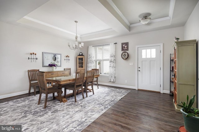 dining space featuring a tray ceiling, dark wood-style flooring, crown molding, a chandelier, and baseboards