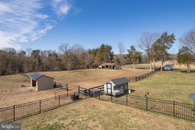 view of yard featuring an enclosed area, a rural view, an outdoor structure, and fence