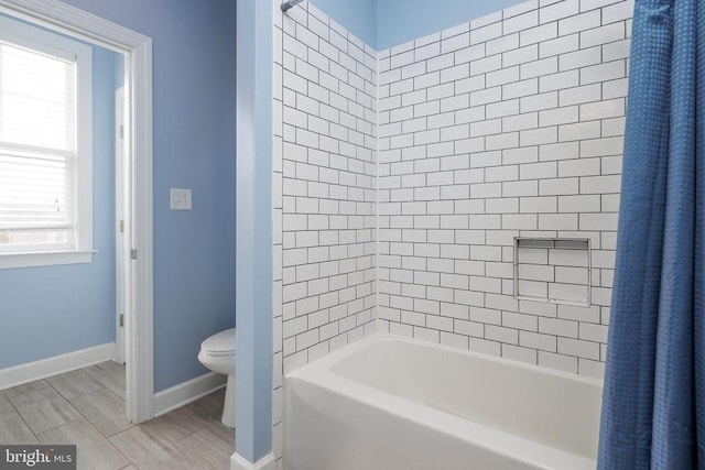 full bath with wood finish floors, shower / bath combo, toilet, and baseboards