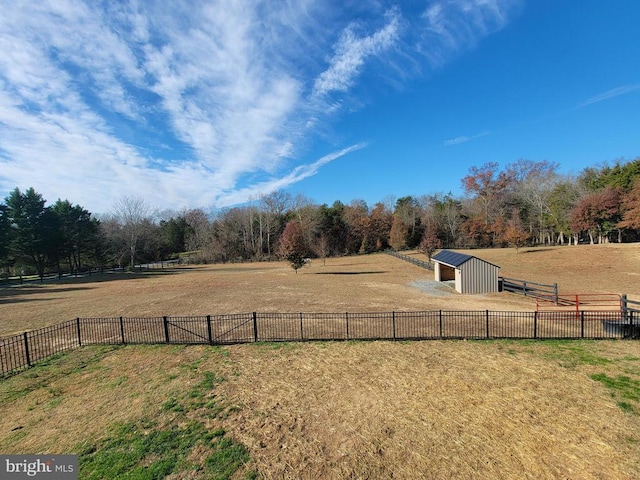 view of yard with a rural view, fence, an outbuilding, and an outdoor structure