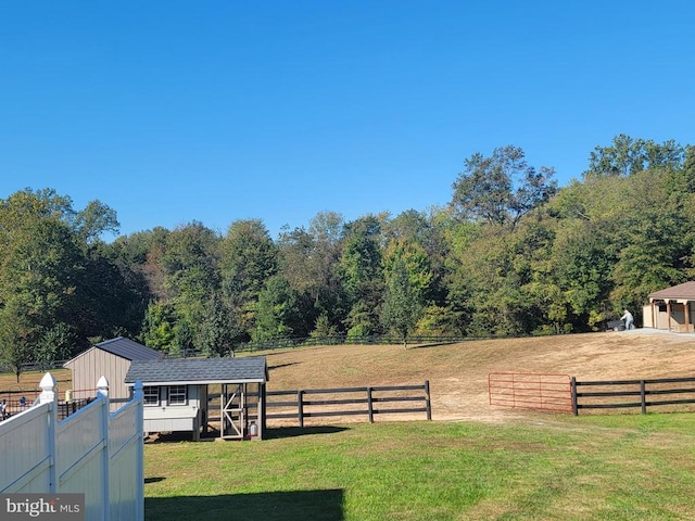 view of yard with a forest view, a shed, an outdoor structure, and fence