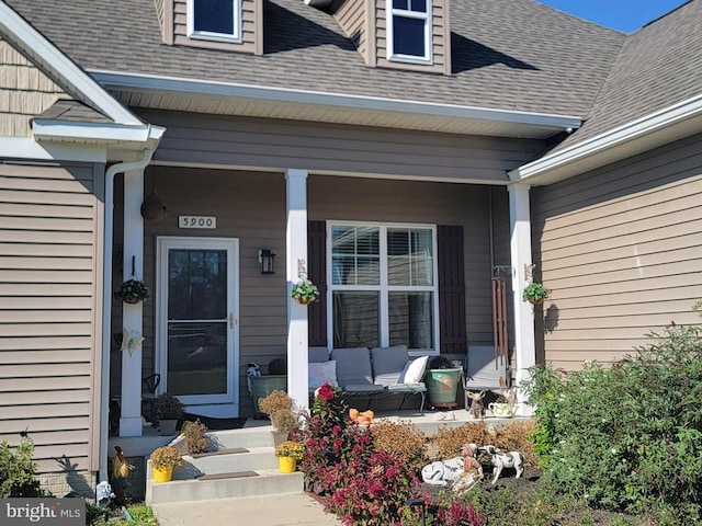 doorway to property with a porch and a shingled roof