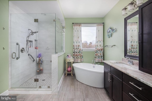 full bathroom with a stall shower, baseboards, wood finished floors, vanity, and a freestanding tub