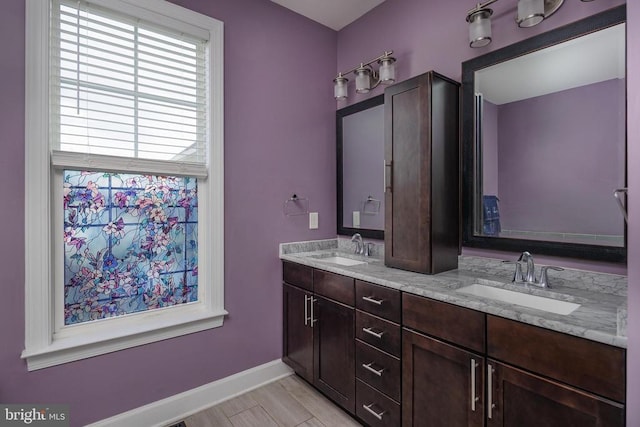 bathroom with a sink, baseboards, and double vanity